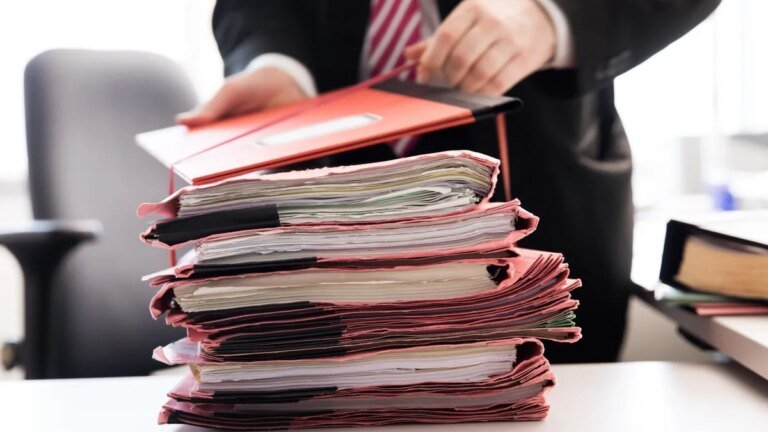 ein-staatsanwalt-steht-vor-einem-stapel-gerichtsakten.jpg