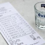 in-einem-griechischen-restaurant-liegt-eine-rechnung-neben-einem-leeren-ouzo-glas.jpg