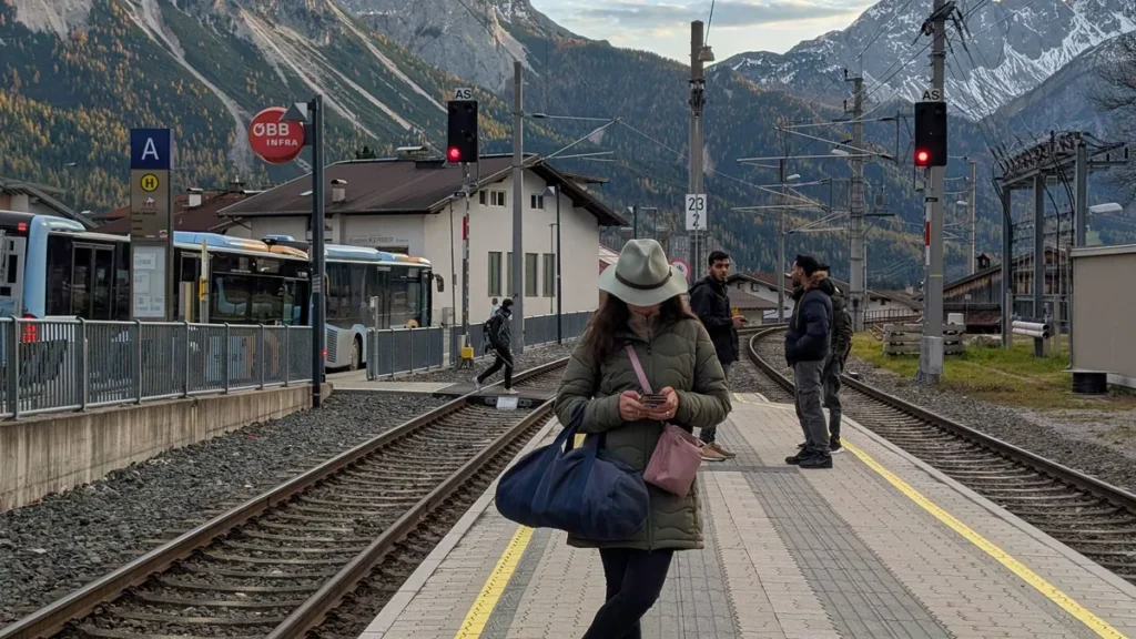 woman-uses-smartphone-at-ehrwald-train-station-with-zugspitze-massif-backdrop-a-young-woman-uses-her.webp