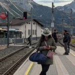 woman-uses-smartphone-at-ehrwald-train-station-with-zugspitze-massif-backdrop-a-young-woman-uses-her.webp