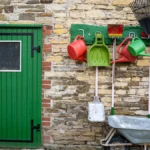 schaufel-giesskanne-besen-und-andere-gartengeraete-haengen-sauber-aufgereit-an-einer-scheunenwand-ga.webp