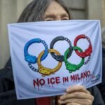 A-protester-holds-a-sheet-of-paper-with-a-printed-depiction-of-the-Olympic-rings-as-handcuffs-and-re.jpeg