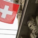 Die-Schweizer-Fahne-weht-ueber-dem-Haupteingang-des-Parlamentsgebaeudes-und-einer-allegorischen-Figu.jpeg