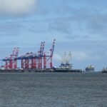 Industriehafen-mit-markanten-roten-Kranen-unter-teilweise-bewoelktem-Himmel-JadeWeserPort-Wilhelmsha.jpeg