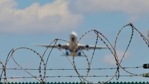 Symbolbild-Abschiebeflug-Ein-startendes-Flugzeug-hinter-einem-Stacheldrahtzaun.jpg