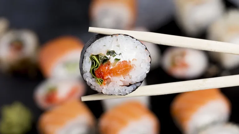 close-up-chopsticks-with-sushi-roll-high-quality-beautiful-photo-concept-close-up-chopsticks-with-su.webp