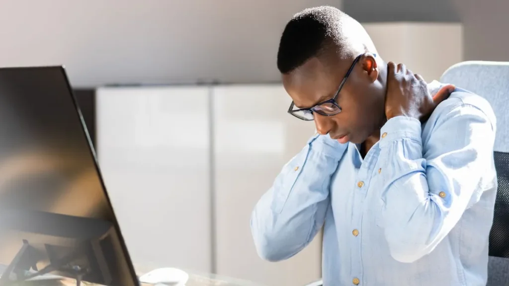 ein-am-computer-sitzender-mann-greift-sich-in-den-nacken-zu-lange-computerarbeit-ist-eine-typischen.webp