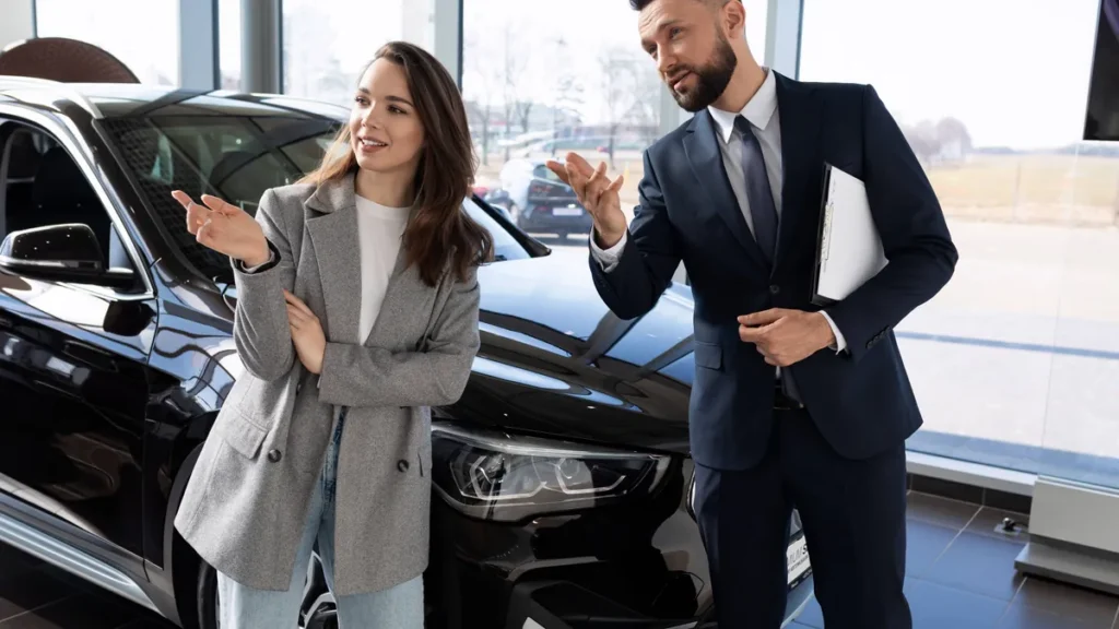 eine-junge-frau-in-einem-autohaus-zusammen-mit-einem-angestellten-waehlt-ein-autohaendler-ein-neues.webp