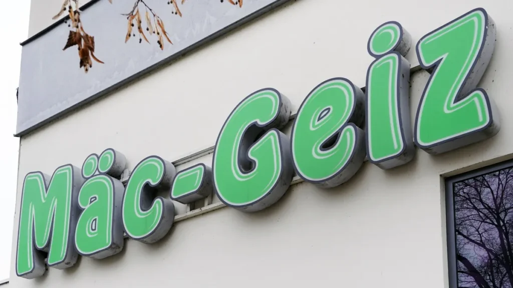 maec-geiz-firmenlogo-leuchtreklame-an-einer-hauswand-deutscher-non-food-discounter-maec-avarice-comp.webp