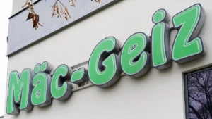 maec-geiz-firmenlogo-leuchtreklame-an-einer-hauswand-deutscher-non-food-discounter-maec-avarice-comp.webp