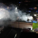 einsatzkraefte-der-feuerwehr-loeschen-den-brand-einer-sporthalle-in-laudenbach-luftaufnahme-mit-eine.webp