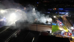 einsatzkraefte-der-feuerwehr-loeschen-den-brand-einer-sporthalle-in-laudenbach-luftaufnahme-mit-eine.webp