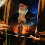 irakische-schiiten-rufen-slogans-tragen-ein-portraet-von-ajatollah-ali-chamenei-und-schwenken-iranis.webp