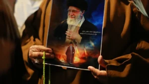irakische-schiiten-rufen-slogans-tragen-ein-portraet-von-ajatollah-ali-chamenei-und-schwenken-iranis.webp