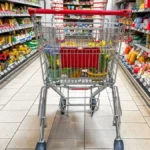 bavaria-germany-april-2-2025-a-shopping-cart-in-the-supermarket-stands-between-full-shelves-the-pict.webp