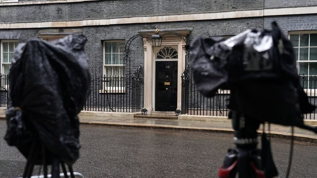 Cameras-are-covered-with-rain-covers-as-journalists-wait-for-a-showing-of-Britain-s-Prime-Minister-K.jpeg