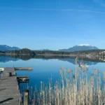 a-panoramic-view-on-the-faaker-lake-in-austrian-alps-the-lake-is-surrounded-by-high-mountains-calm-s.webp