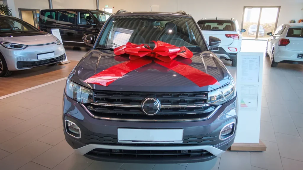 eine-grosse-rote-schleife-ist-auf-der-motorhausbe-eines-neuwagens-a-big-red-bow-is-on-the-engine-hoo.webp