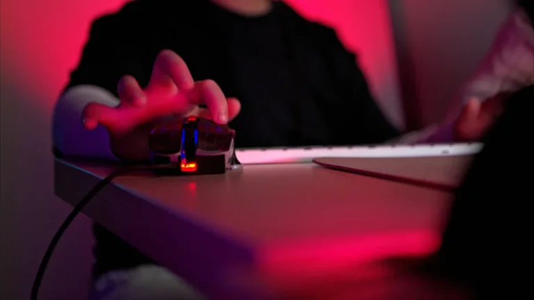 nahaufnahme-einer-person-die-eine-gaming-maus-mit-rgb-beleuchtung-neben-einer-tastatur-in-einem-dunk.webp