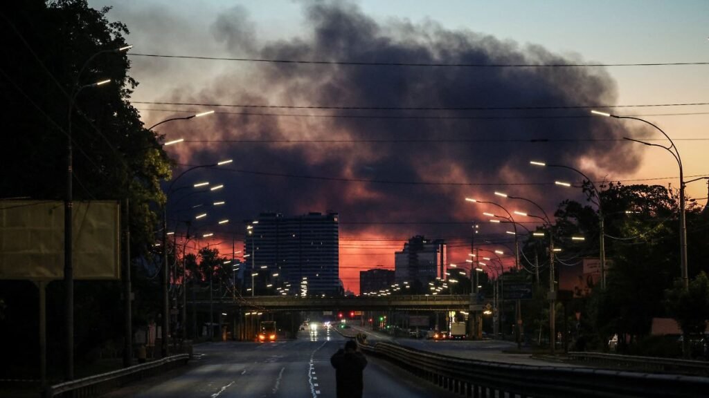 A-man-takes-a-picture-of-a-street-as-smoke-rises-in-the-background-after-an-overnight-Russian-missil.jpeg