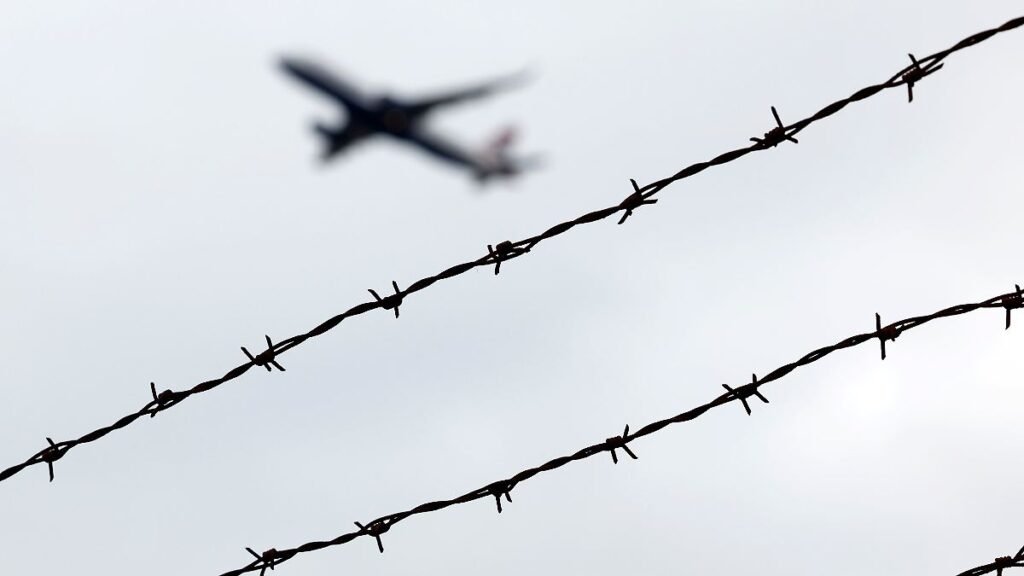 Ein-Flugzeug-startet-am-Flughafen-Koeln-Bonn-gesehen-durch-Stacheldraht-ausserhalb-des-Rollfelds-Der.jpeg