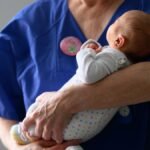 Eine-Kinderkrankenschwester-haelt-ein-Neugeborenes-nach-dem-Wiegen-auf-der-Neugeborenenstation-im-DR.jpeg