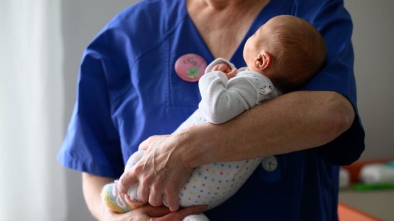 Eine-Kinderkrankenschwester-haelt-ein-Neugeborenes-nach-dem-Wiegen-auf-der-Neugeborenenstation-im-DR.jpeg
