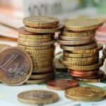 Gestapelte-Geldmuenzen-liegen-auf-Geldscheinen.jpg