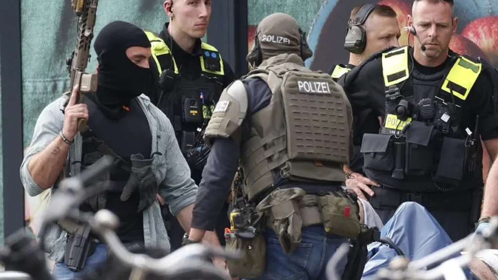 spezialeinsatzkraefte-der-polizei-bewachen-den-mutmasslichen-taeter-der-auf-einer-krankentrage-liegt.webp