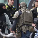 spezialeinsatzkraefte-der-polizei-bewachen-den-mutmasslichen-taeter-der-auf-einer-krankentrage-liegt.webp